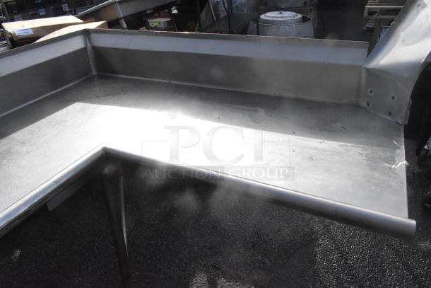 Stainless steel L-shaped clean side dishwasher table, sturdy and polished, shows minor surface wear. Ideal for commercial kitchens.