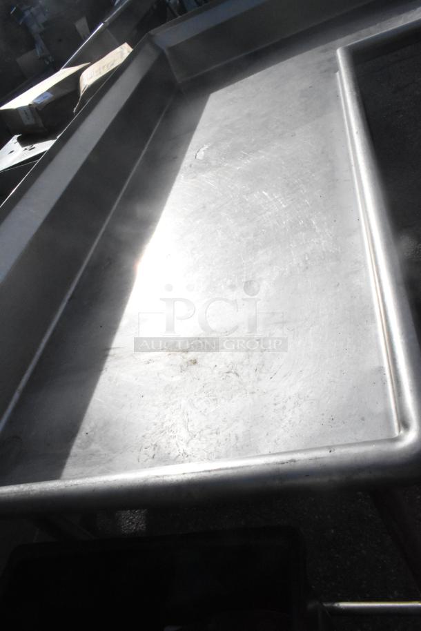 Stainless steel L-shaped clean side dishwasher table; sturdy construction, excellent condition, slightly reflective surface.