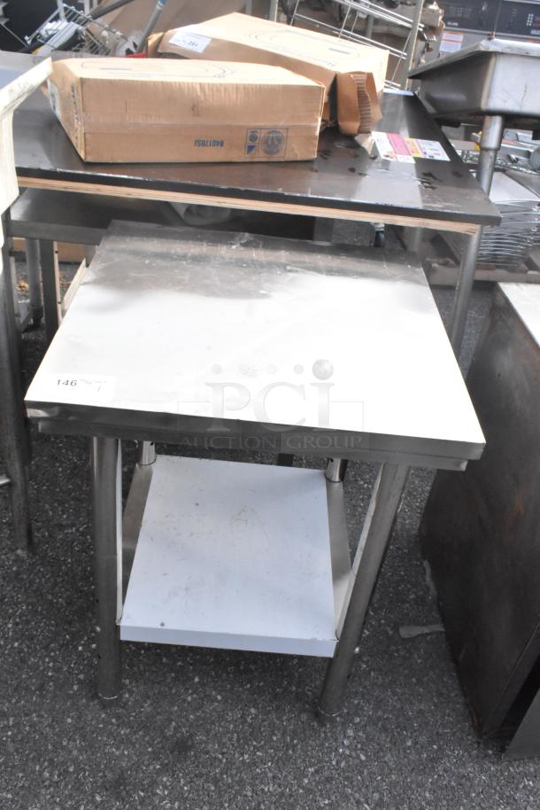 Stainless steel table with metal under shelf, shows some surface wear. Ideal for kitchens or restaurants.