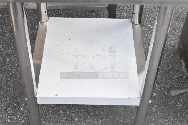 Stainless steel table with a metal lower shelf, showing slight surface wear. Durable construction suitable for various uses.