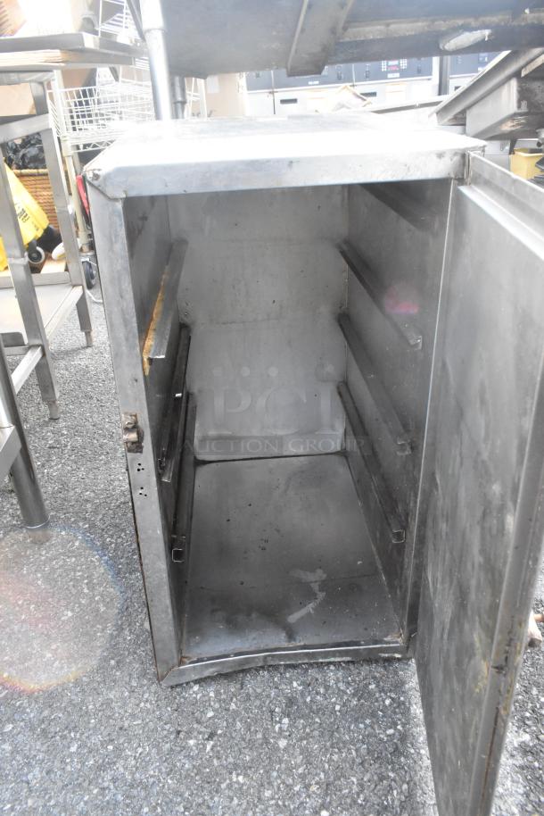 Metal portable enclosed pan rack with open door, showing interior shelf rails. Slight rust and wear visible on edges.