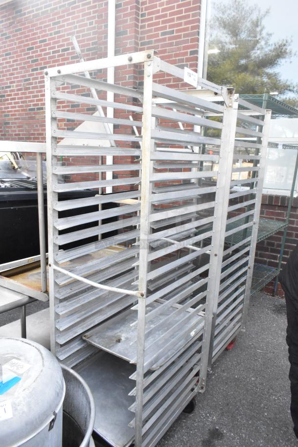 Two metal commercial pan transport racks on casters, outdoors. Solid construction; used condition. Auction label "152."