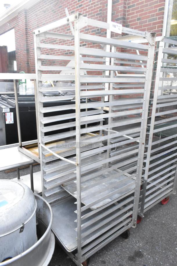 Two metal commercial pan transport racks on durable casters, featuring multiple shelving slots, in used condition.
