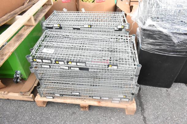 Pallet lot of chrome finish wire shelves, stacked, featuring visible product tags and labels. Condition appears new.