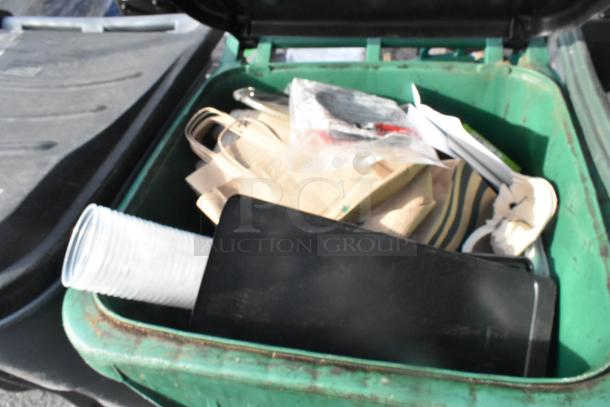 Two green poly trash cans open, containing assorted items like disposable cups and bags. Condition appears used.