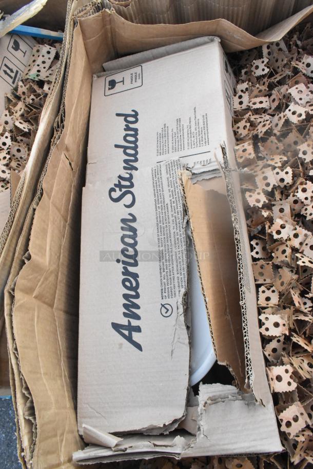 Damaged box of American Standard products, partially open, showing packaging material. Box marked "Fragile."