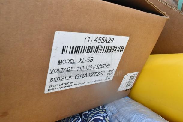 Cardboard box with Xlerator Hand Dryer, Model XL-SB, Serial GRA127267, voltage 110-120V, and yellow tubes visible.