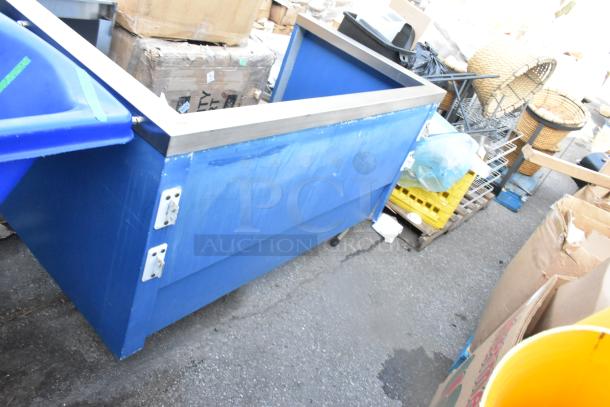 Blue bin on casters with metal trim and locking brackets, showing signs of wear. Ideal for storage or transport use.