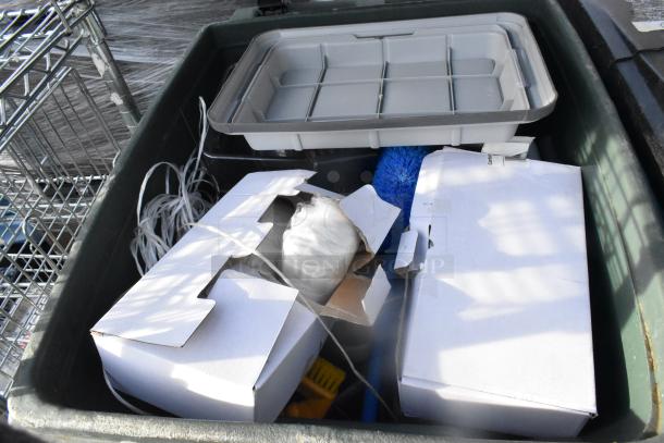 Alt text: Poly trash can filled with various items including white boxes, a blue brush, and a gray storage container.