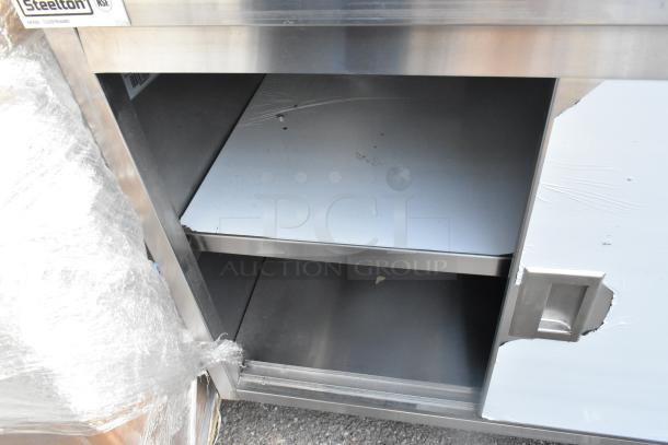 Brand new Steelton 30" x 48" stainless steel table with sliding doors, midshelf, and 6" backsplash. Scratch and dent condition.