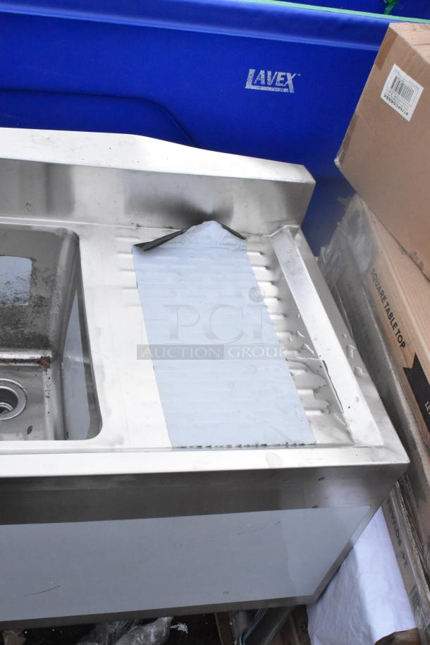 BRAND NEW Regency 3-bowl underbar sink with two drainboards, 60"x18.75". Scratch and dent visible, stainless steel design.