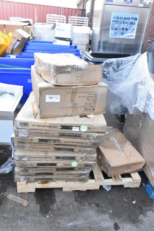 Stack of boxed items including Choice food pan carriers, Lancaster table tops, and fry pans on pallet. New condition.