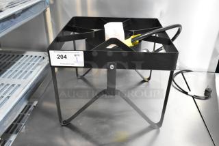 Black metal propane gas stock pot range on sturdy legs, appears new. Tag reads "204 QTY 1." Includes power cord.