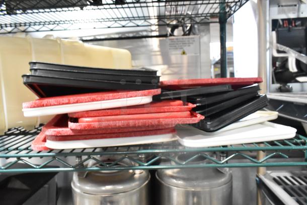 Two-tier shelf with assorted poly bins, lids, red and black trays, metal hoppers, and kegs in kitchen setting.