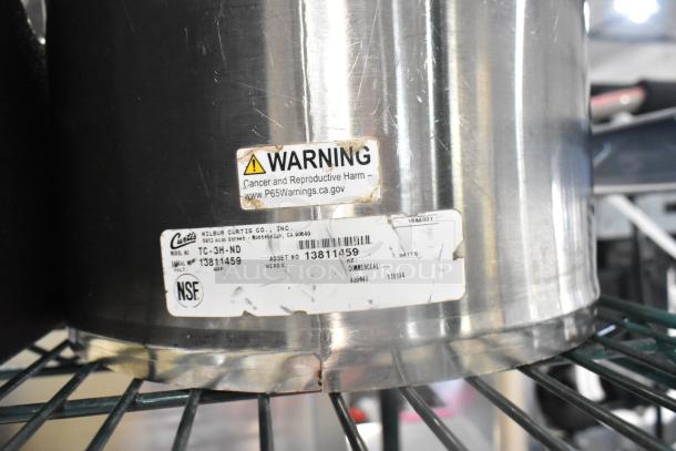 Stainless steel iced tea dispenser with asset tag "Wilbur Curtis Co.," model TC-3H-ND. Warning label included.