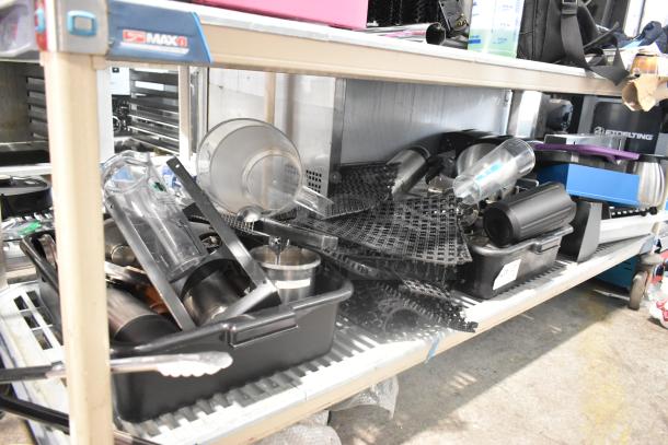 Tiered shelf displaying bus bins, mat pieces, poly pitchers, and assorted kitchen items. Some labels visible, moderate wear.