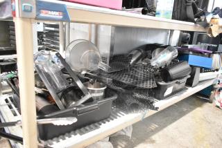 Tiered shelf displaying bus bins, mat pieces, poly pitchers, and assorted kitchen items. Some labels visible, moderate wear.