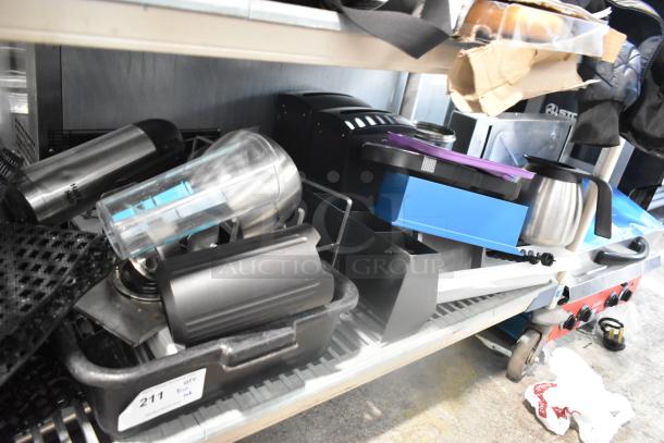 Tiered shelf with assorted items: bus bins, mat pieces, poly pitchers, and various kitchenware. Includes labels and bins.