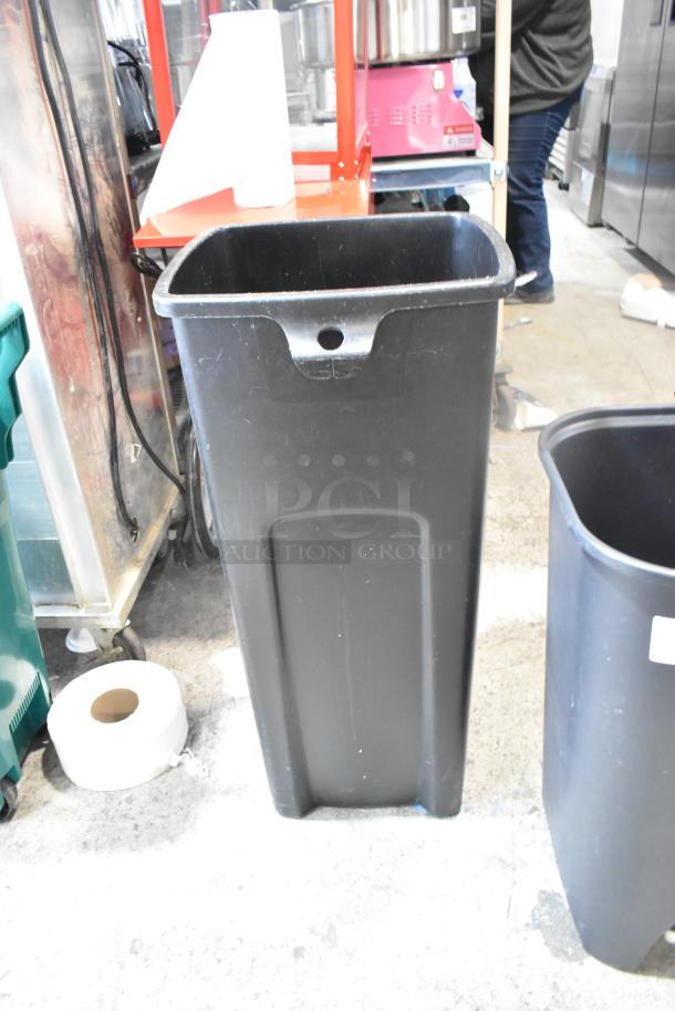 Two black poly trash cans, standing upright. Durable, cylindrical design. No visible damage. Auction item: bid doubles.