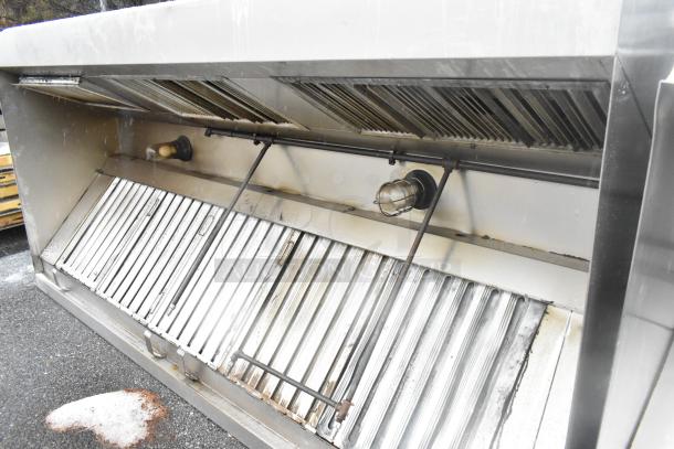9.5' stainless steel commercial grease hood with filters and lights, in used condition, showing visible grill and wiring.
