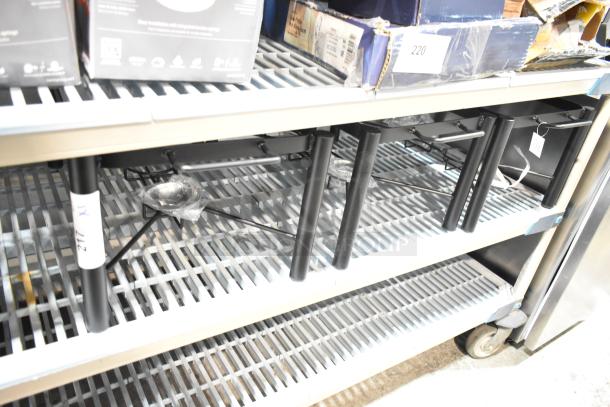 Three new Acopa 407PLSTNDFL 8 Qt. wrought iron chafer stands on shelf. Minor scratch and dent condition.