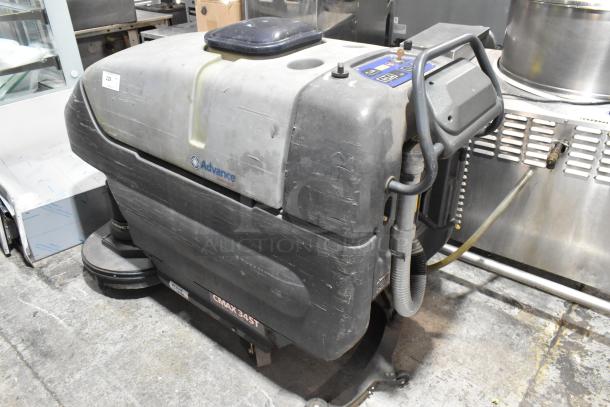 Nilfisk Advance floor cleaning machine, CMAX 34ST model, used condition with visible wear, features control panel, hoses.