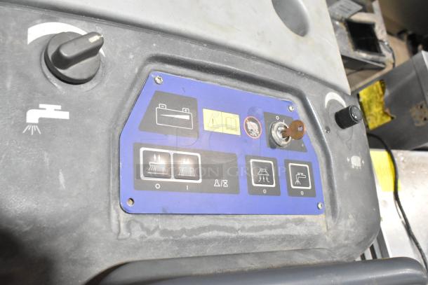 Nilfisk Advance floor cleaning machine control panel with operational icons, key, and water spray symbol, showing moderate wear.