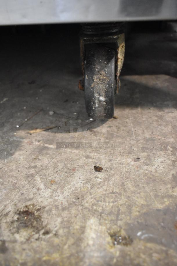 Turbo Air TST-48SD-D2 caster wheel, slightly worn; part of stainless steel commercial sandwich prep table.