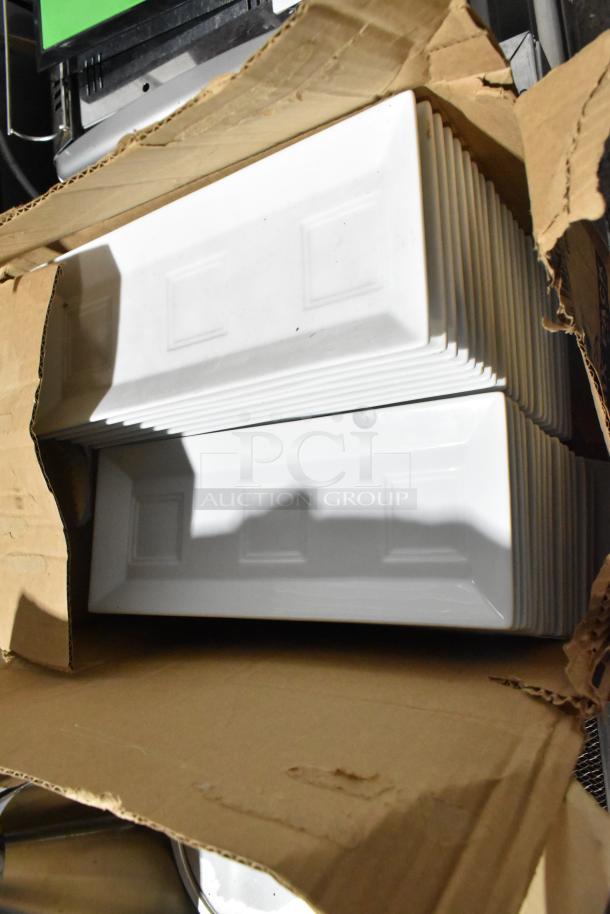 Box of white rectangular ceramic plates, slightly visible, in good condition inside open cardboard packaging.