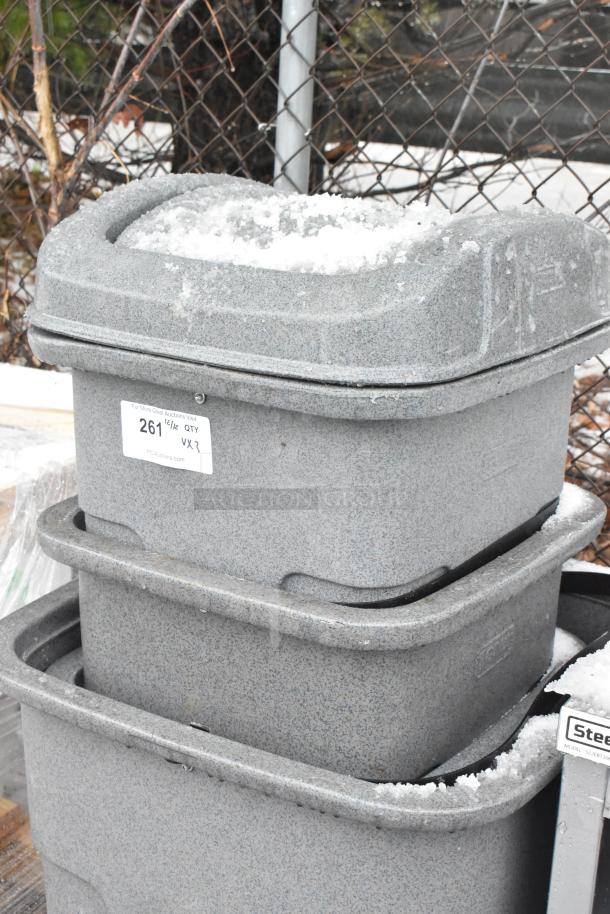 Three brand new gray poly trash cans with minor scratches, stacked outdoors. Marked with auction label 261½ QTY VXR.