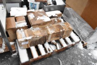Snow-covered pallet with multiple boxes, including 600SRS36S Regency Spec Line speed rail, showcasing visible labels.