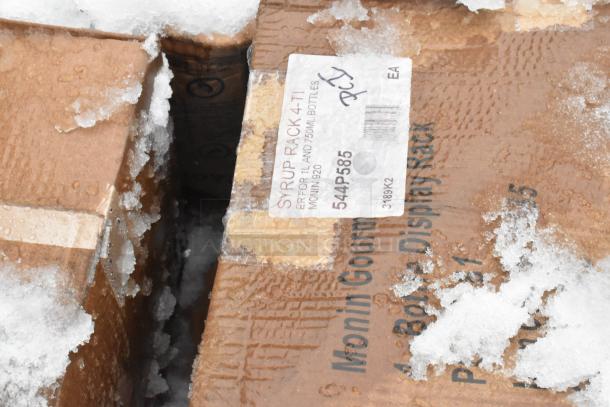 Boxes labeled "544P585 Monin Syrup Rack" in snowy condition; part of 8 new scratch and dent auction items.