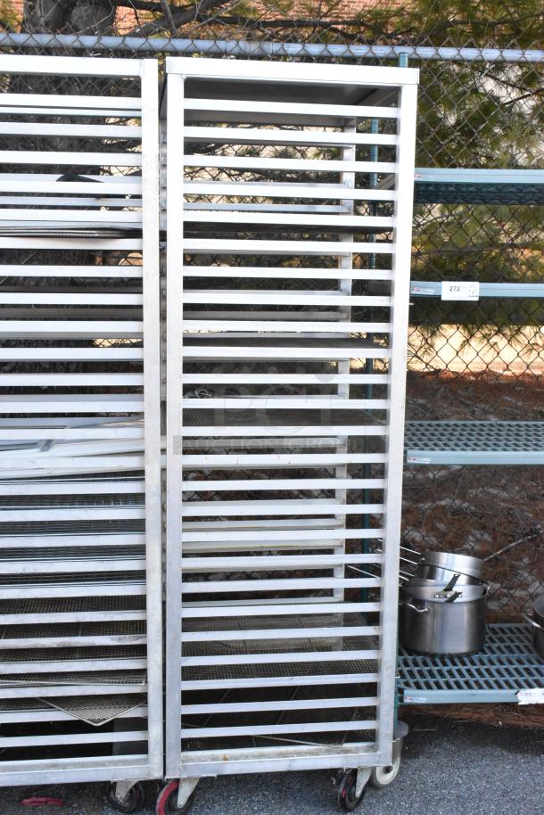 Two metal commercial pan transport racks on commercial casters, featuring multiple slats for tray storage.