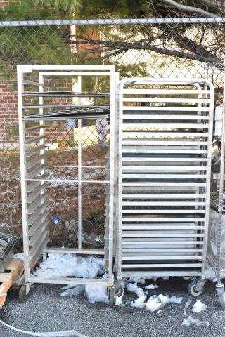 Two metal commercial pan transport racks with multiple horizontal slots, mounted on durable commercial casters.