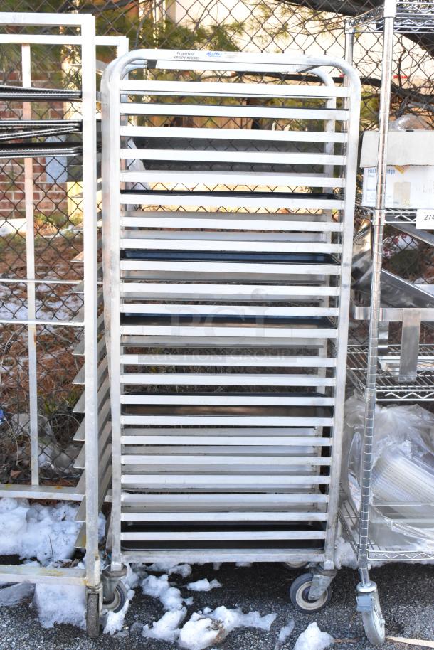 Metal commercial pan transport rack with multiple shelves and commercial casters, labeled "Property of Krispy Kreme."