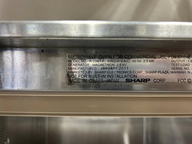 Sharp R22GTF stainless steel commercial microwave, 1,200W, touch controls, tested working, 20 programmable memories, tag shows model info and origin.