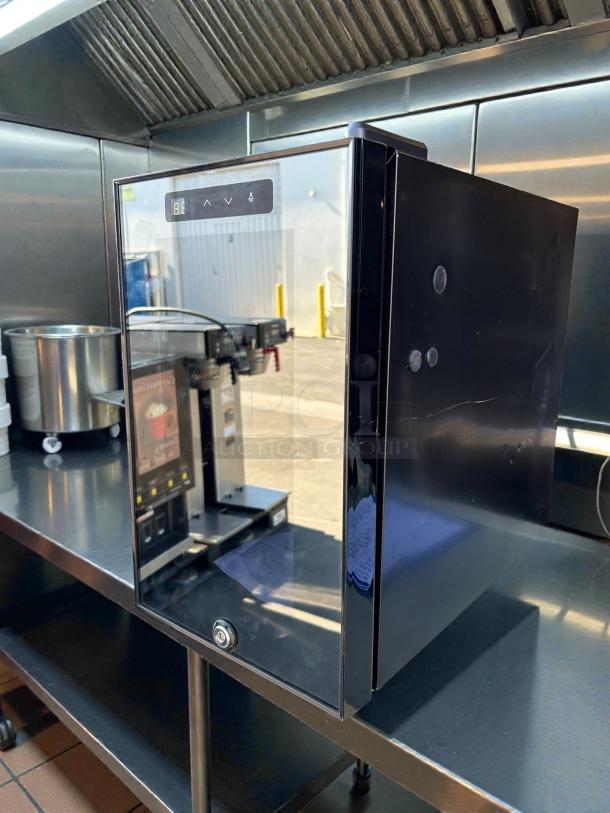 Countertop black refrigerator, like new, with plug and keys. Features digital display and glossy finish.