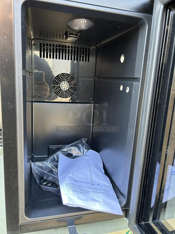 Countertop black refrigerator in like-new condition with plug, keys, and manual. Inner cooling fan visible.