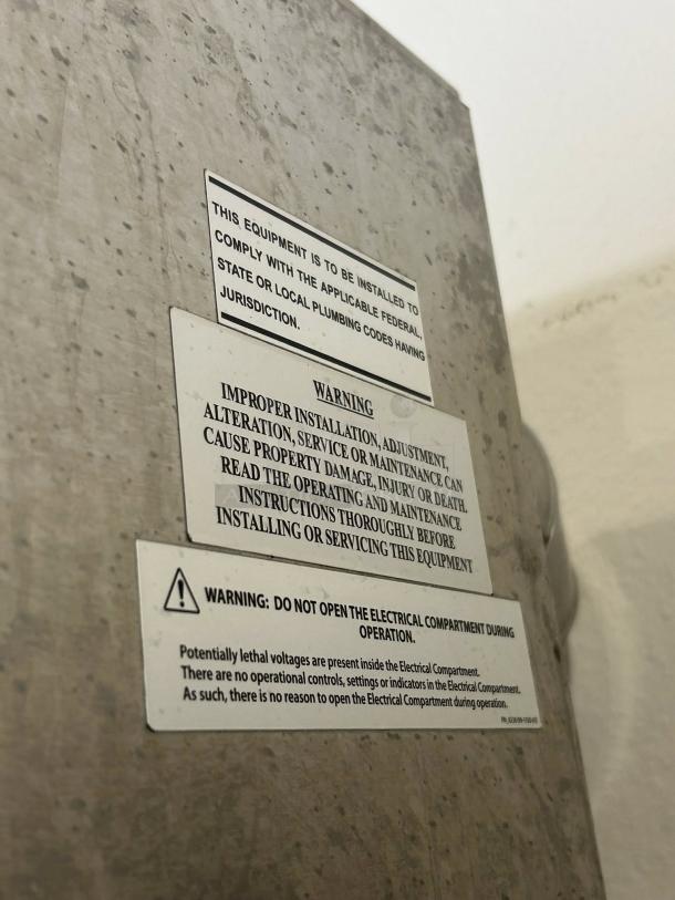 Alt text: Hardt Inferno 3500 commercial rotisserie labels showing installation and safety warnings on stainless steel surface.