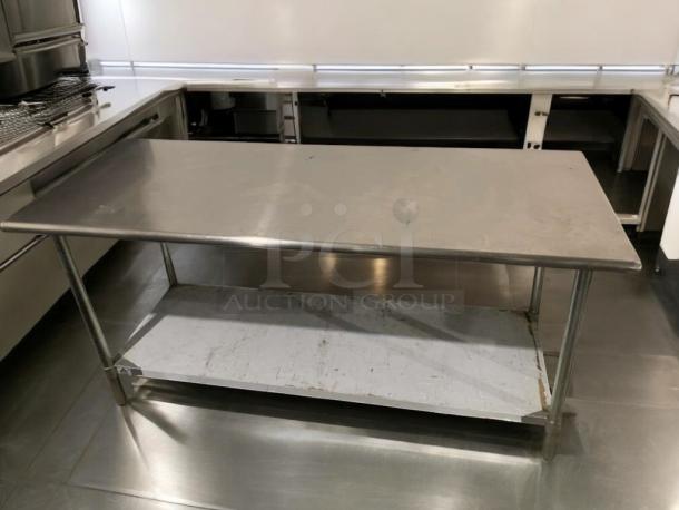 Stainless steel commercial work table, heavy duty, in exceptional condition, features sturdy legs and spacious lower shelf.