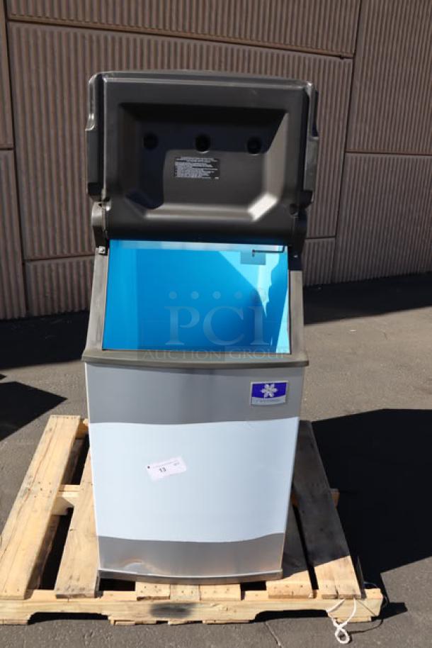 Manitowoc D420 ice storage bin on pallet, open lid, minor dents and scratches, 383 lb capacity, visible label with model details.