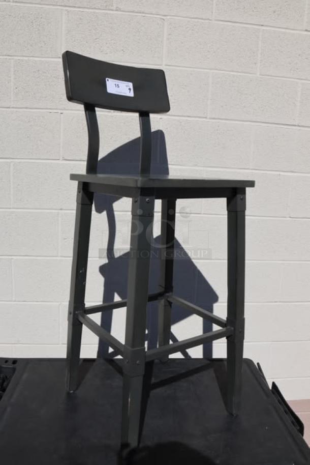 Brand new bar height wood stool with back and footrest, black finish, tag indicates lot number, slightly scratched condition.