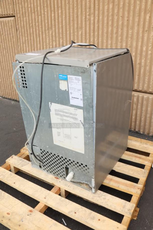 Brand new Scotsman UN1520A-1A nugget ice machine, 57 lb. bin, 115V, air-cooled, minor dents visible, label displays model/serial info.