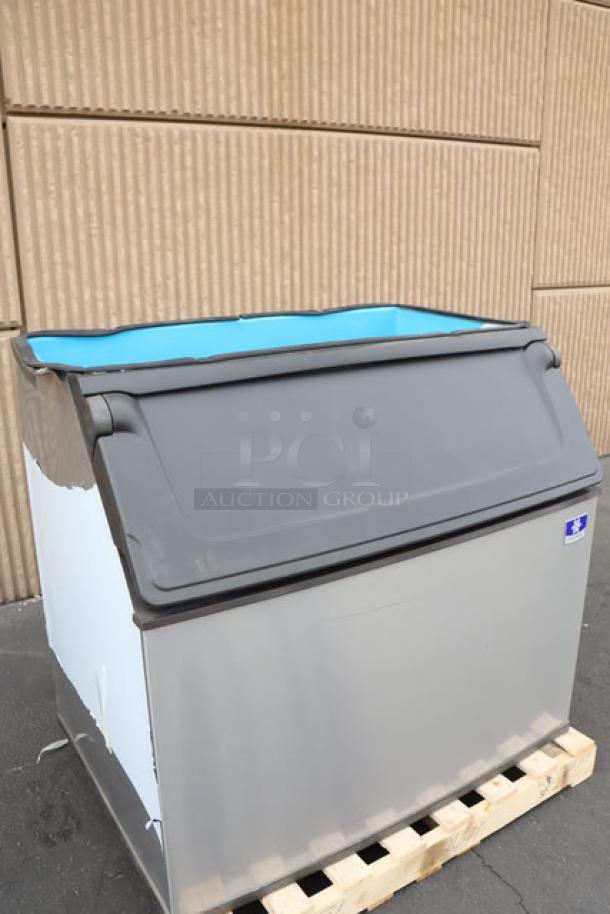 Brand new Manitowoc D970 ice bin, 882 lb capacity, minor scratches, dent, gray exterior, on pallet. Serial: 1121219180.