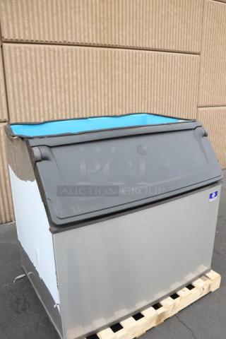Brand new Manitowoc D970 ice bin, 882 lb capacity, minor scratches, dent, gray exterior, on pallet. Serial: 1121219180.