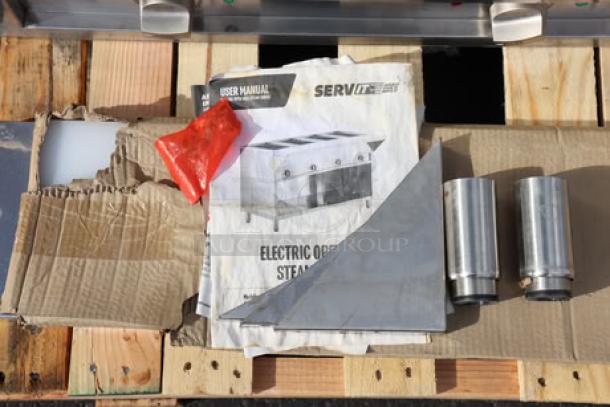 BRAND NEW SCRATCH-N-DENT ServIt 423ESTSWOPB Electric Steam Table parts on pallet; manual, panels, and cylindrical components visible.