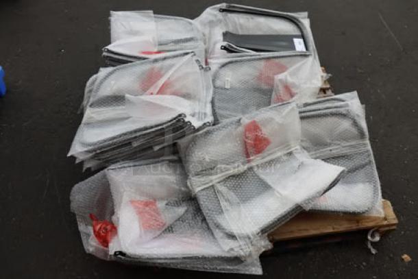 Brand new Lancaster Table & Seating metal chair backrests, black, bundled in bubble wrap on a pallet, 35 pieces.