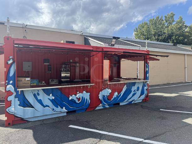 Custom 20' mobile beach bar container with blue wave murals, equipped with beer coolers, sinks, frozen drink machine, and sound system.