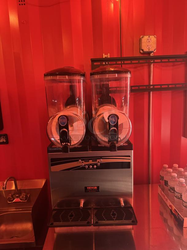 VEVOR frozen drink machine inside bright red "Sandlot Beach Bar" container, next to a sink and bottled water stack.