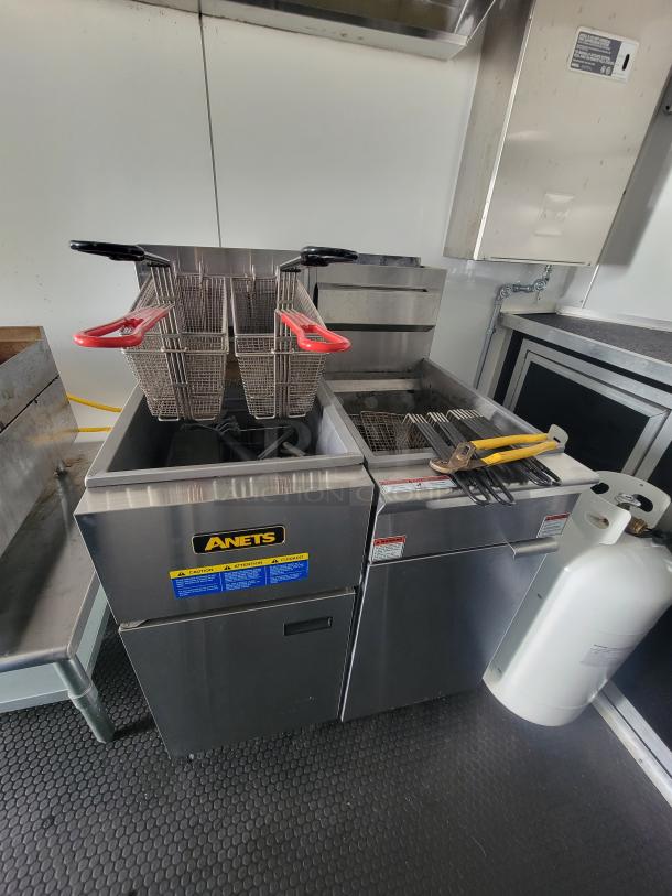 Anets dual fryers in the 2021 Covered Wagon mobile food trailer, featuring stainless steel finish, with red-handled baskets and propane tank.